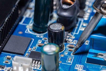 The hand holding the tin, a soldering iron solder the chip in place. computer repair. macro...