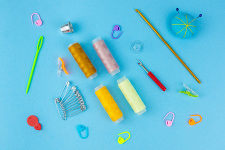 Sewing accessories and fabric on a blue background. Sewing threads, needles, pinsの写真素材