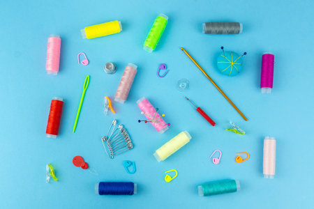 Sewing accessories and fabric on a blue background. Sewing threads, needles, pinsの写真素材