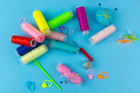 Sewing accessories and fabric on a blue background. Sewing threads, needles, pinsの写真素材