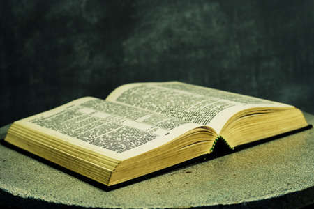 Bible on a round white table. Beautiful dark background. Religious concept.