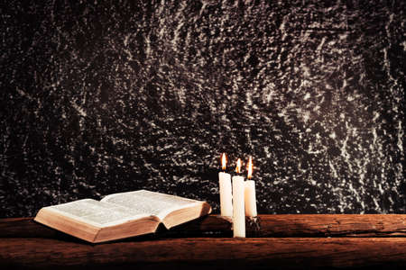 Bible and candle on a old oak wooden table. Beautiful dark background.Religion concept.の写真素材