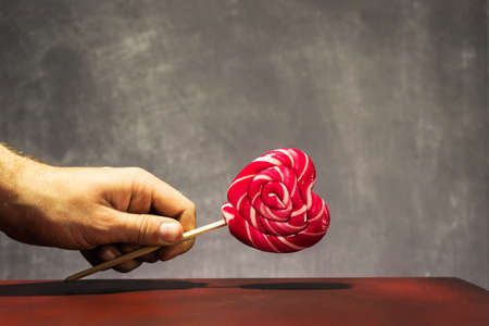 Heart shaped lollipop on a wooden tableの写真素材