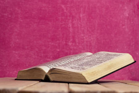 Bible and the crucifix on a new wooden table. Beautiful pink background. Religion conceptの写真素材