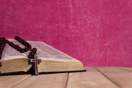 Bible on a new wooden table. Beautiful pink background. Religion conceptの写真素材