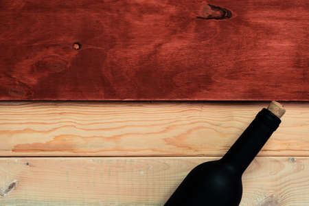 Black bottle of red wine on a red and new wooden table. Beautiful backgroundの写真素材
