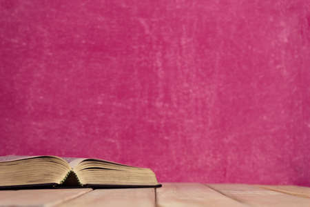 Bible and the crucifix on a new wooden table. Beautiful pink background. Religion concept