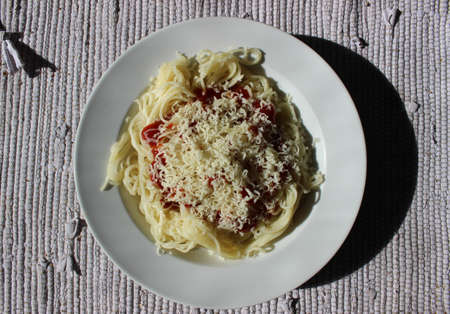 Spaghetti with ketchup and cheese parmesan on a plate.の写真素材