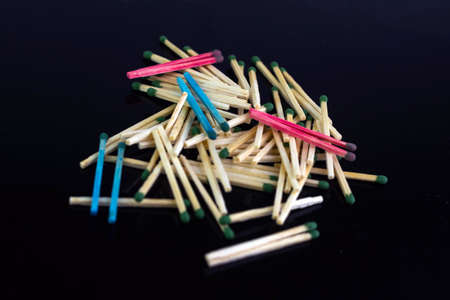 homosexuality concept: several pairs of blue and pink matches in front of a pile of ordinary matches, black background, short focus, limited lighting, toningの写真素材