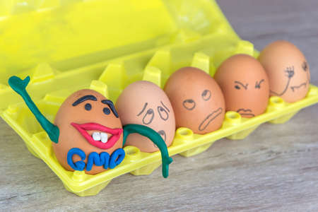 GMO: the joyful genetic monster-egg smiles happily and waving a hand among a variety of ordinary...