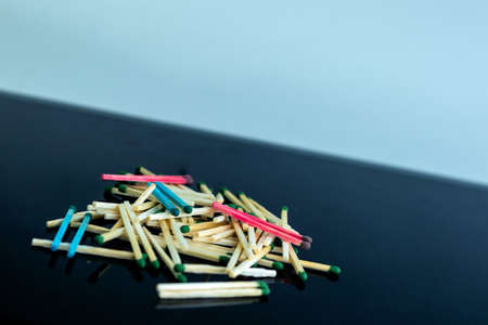 homosexuality concept: several pairs of blue and pink matches in front of a pile of ordinary matches, black background, short focus, limited lighting, toningの写真素材