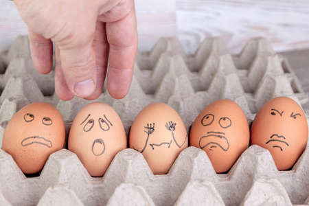 few eggs in the tray look with horror at the man's arm reaching out for themの写真素材