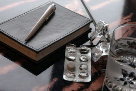 suicide: notepad, a glass of water and blisters on the table, short focus, toning
