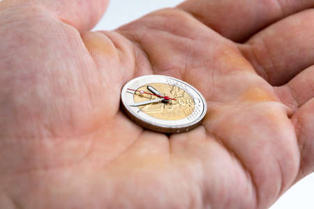 middle class savings: 2 euro coin with hour hands on the male palm, short focus, toning, closeの写真素材