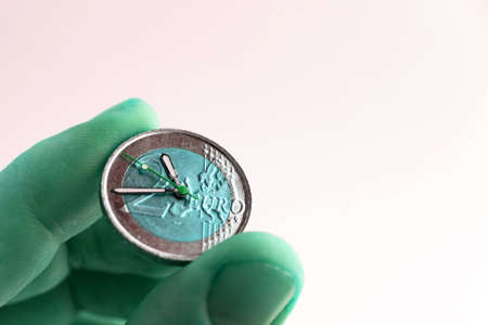 time of profitable investment: 2 euro coin with hour hands, short focus, color change, closeの写真素材