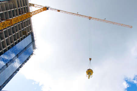 construction of buildings: the lifting crane bears a bucket with concrete, against a background of...