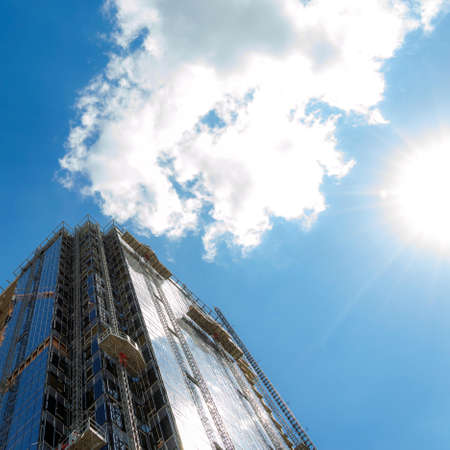 building, scaffolding and lifts against the sky and sunの写真素材