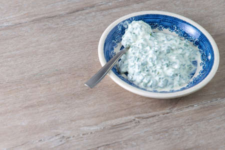 dinner sauce: sour cream and onions in a bright porcelain plate on a wooden tableの写真素材