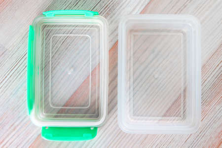 eco-friendly transparent plastic food storage container, color lid, on a wooden table, close, short focusの写真素材