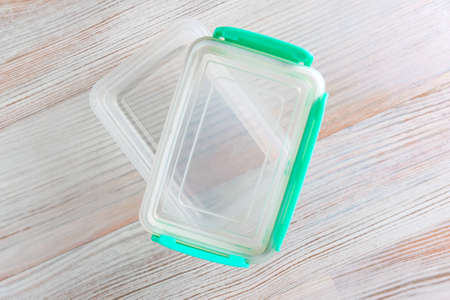 eco-friendly transparent plastic food storage container, color lid, on a wooden table, close, short...
