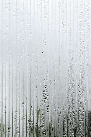 condensate and water droplets on corrugated glass, blurred contours of the street nature, for the...