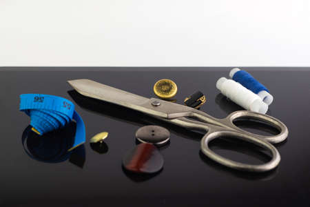vintage big seamstress scissors, measuring blue tape and buttons on black background. short focusの写真素材