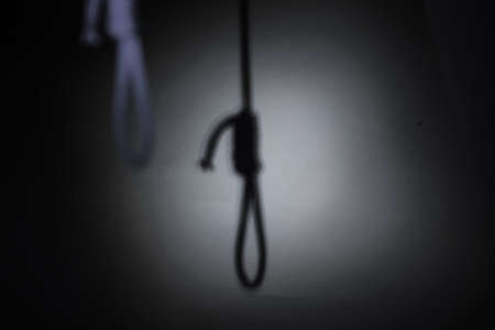 blurred shadow of the loop of the gallows on the light wall, darkness, reduced colorの写真素材