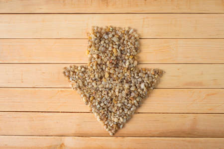 arrowhead made of coarse sand on a wooden table