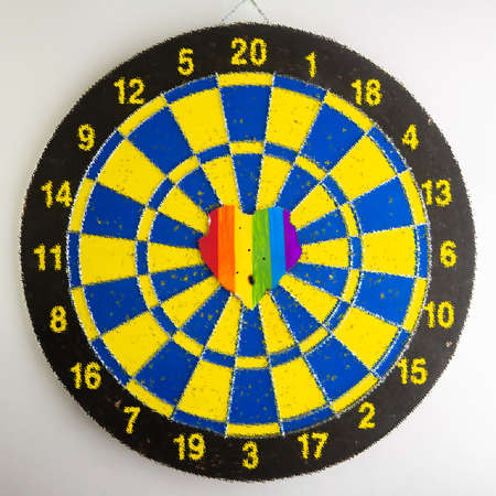 Concept - harassment of the freedom of the LGBT community: burned and torn rainbow heart pierced by darts, short focus, blurred backgroundの写真素材