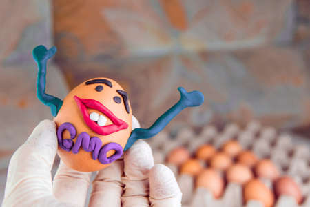 GMO: the joyful genetic monster-egg smiles happily and waving a hand among a variety of ordinary...