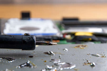 smoking soldering iron over a metal board, a computer board with microchips behind
