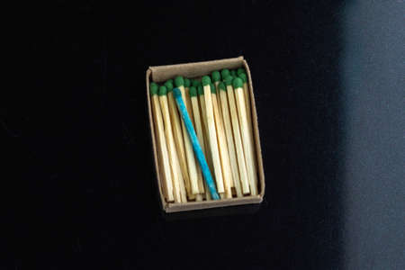 homosexuality concept: one blue match in a box with ordinary matches, black background