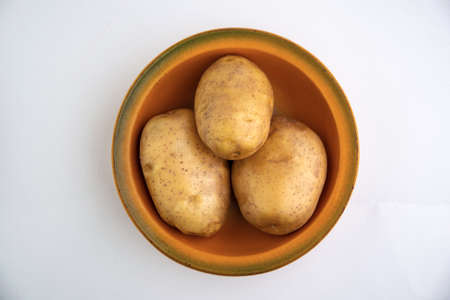 vegan diet: fresh raw organic potatoes on a plate, isolated on white, short focusの写真素材