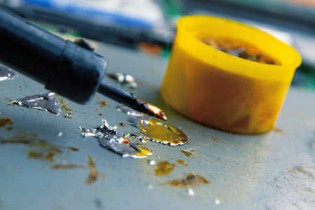 hot smoking soldering iron with rosin and tin, molten metal drops, electronic devices in the background, selective focus, closeの写真素材