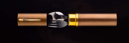 set of dining items for camping: small spoon and fork, storage case, dark backgroundの写真素材