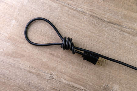 concept of energy dependence: hinge loop made of an electric cord with a plug, on a wooden...