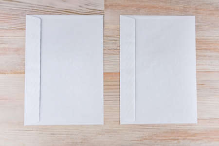 two empty white envelopes on a wooden desk