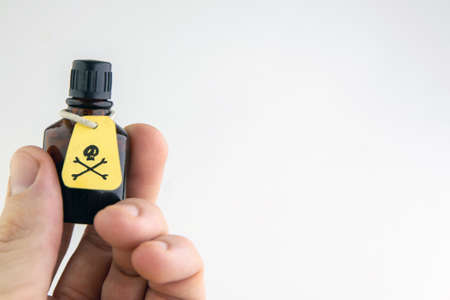 a vial of poison in a manâs hand on a light background, overexposure, toningの写真素材