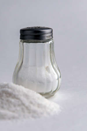 mineral diet: saltcellar with the letter "S" next to a pile of sea salt fluoridated salt on the tableの写真素材