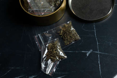 drug trade: a bag of hemp next to many packaged doses of cannabis lie in a metal can