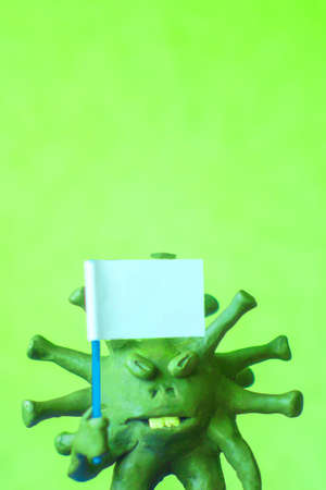 coronavirus COVID-19 defeated! Cartoon caricature of a virus surrenders, waving a white flag. Short focus, toning.の写真素材