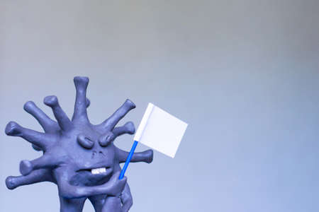 coronavirus COVID-19 defeated! Cartoon caricature of a virus surrenders, waving a white flag. Short focus, toning.の写真素材