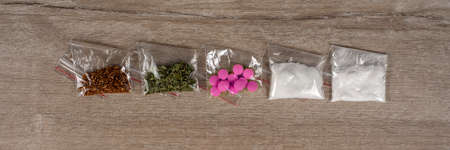 death row concept: tobacco, weed, MDMA tablets, amphetamine crystals, heroin in plastic bags, on a light background. Enhanced contrast, partial blur.の写真素材