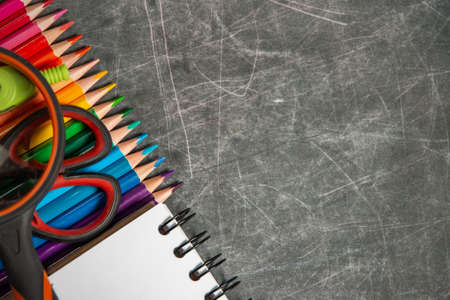 multicolored school supplies lie on black chalkboard, short focus, partial blur