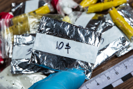 evidence of smuggling traffic: Packaging of a narcotic substance in the hand of a forensic expert against the background of other arrested materials, cocaine, heroin, spiceの写真素材