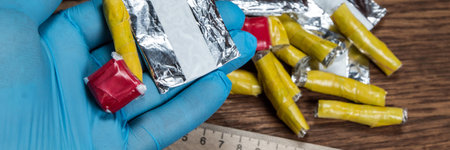 evidence of smuggling traffic: Packaging of a narcotic substance in the hand of a forensic expert against the background of other arrested materials, cocaine, heroin, spiceの写真素材