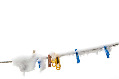 winter background: clothesline covered with snow, several colored clothespins, selective focusの写真素材