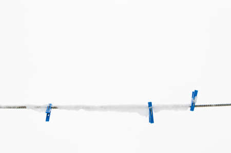 winter background: clothesline covered with snow, several blue clothespins, selective focusの写真素材