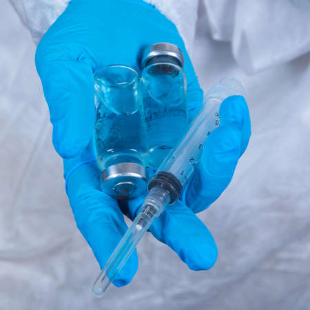 sars-cov-2 vaccination: a health worker with a vaccine and a syringe in his hands