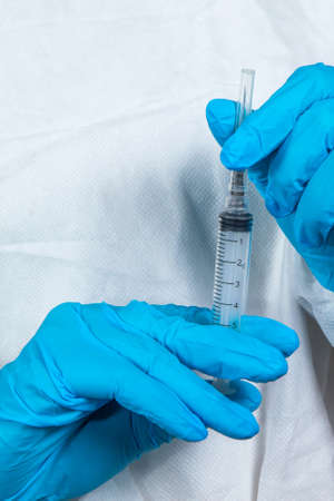 covid-19 sars-cov-2 vaccination: a health worker with a vaccine and a syringe in his hands